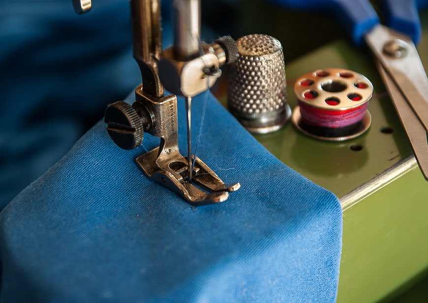 Close-up of vintage sewing machine needle on blue fabric