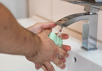 Close-up of hands washing with soap under running water tap