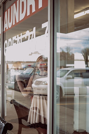 Woman in dress looking through laundry shop window