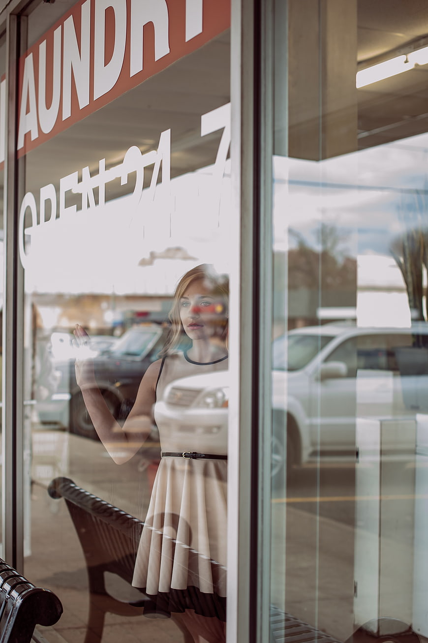 Woman in dress looking through laundry shop window