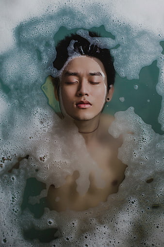 Man relaxing in bubble bath with eyes closed