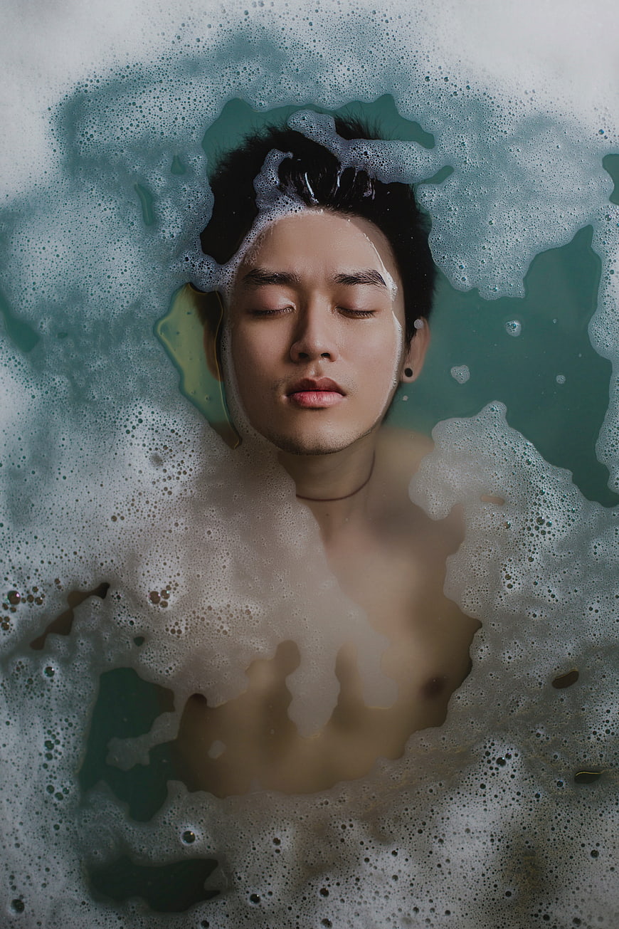 Man relaxing in bubble bath with eyes closed