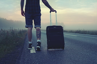 Man Walking on Road with Luggage at Sunset