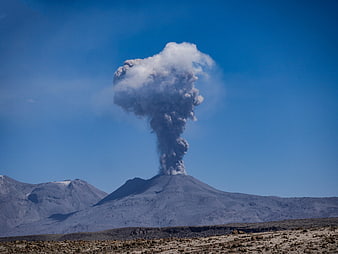 Active Volcanic Eruption With Ash Cloud Rising Over Mountainous Landscape