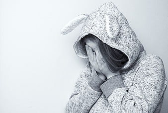 Sad woman in bunny hoodie covering face in despair