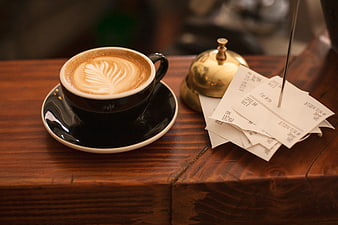 Latte Art Coffee Cup with Service Bell and Receipts on Wooden Counter