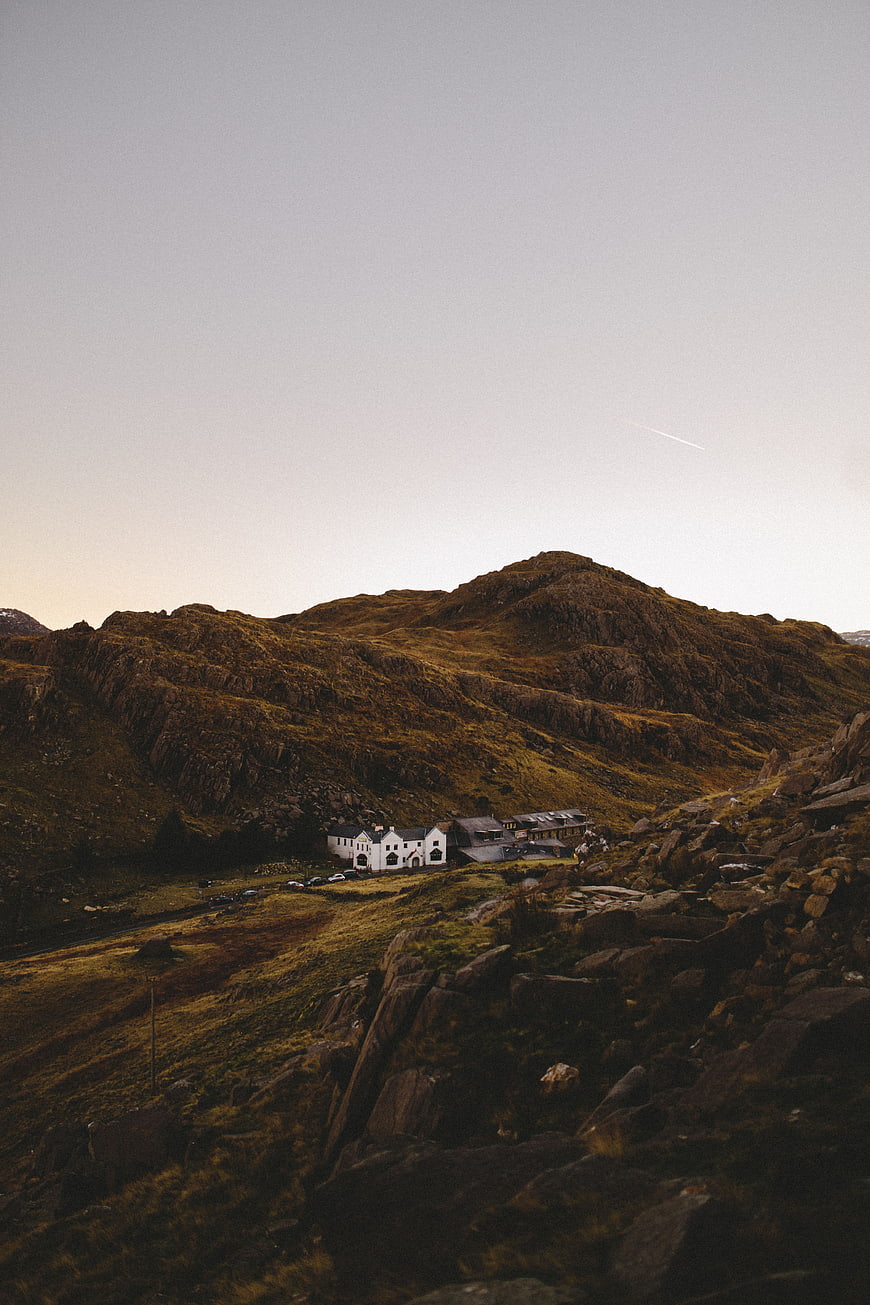 Lone white building nestled in rugged mountain landscape at dusk