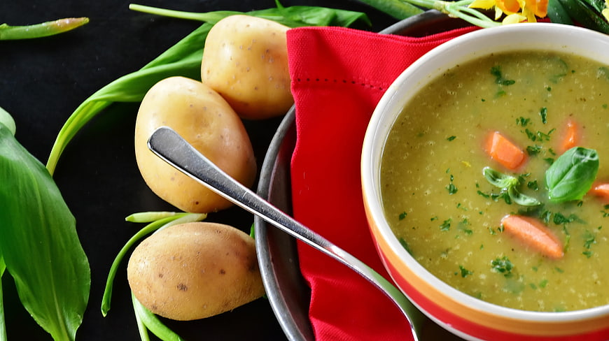 Bowl of creamy potato soup with carrots and wild garlic
