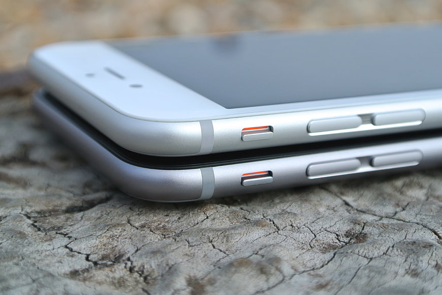 Close-up of two stacked silver smartphones on textured wood