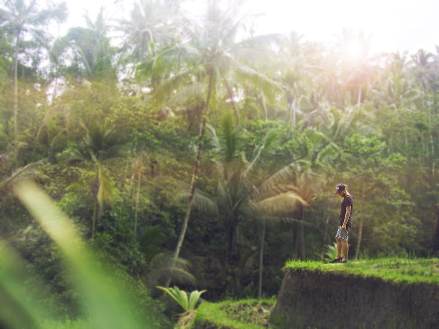 Man standing on cliff edge overlooking tropical jungle forest