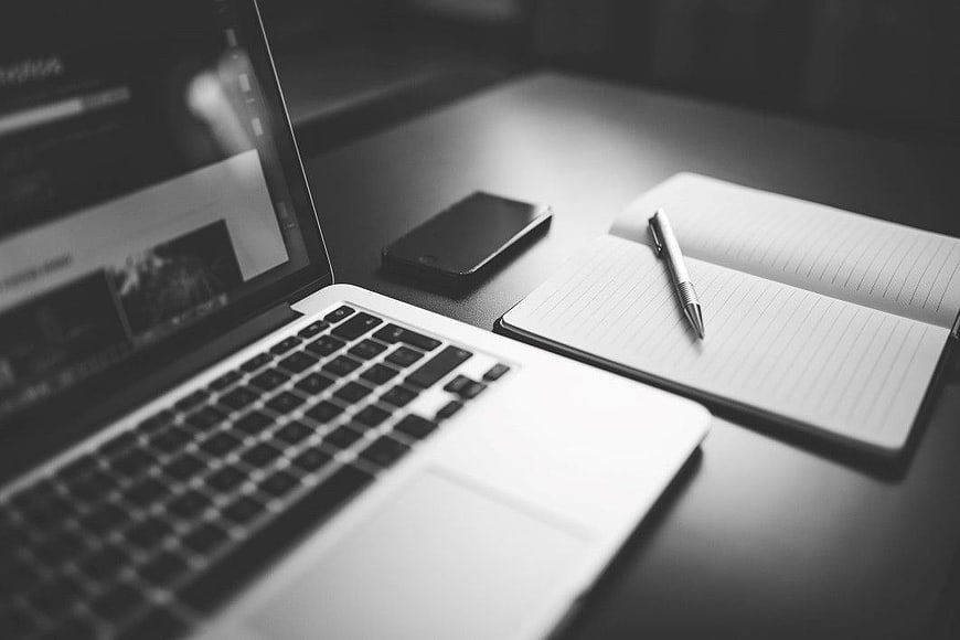 Black and White Workspace with Laptop, Smartphone, and Notebook