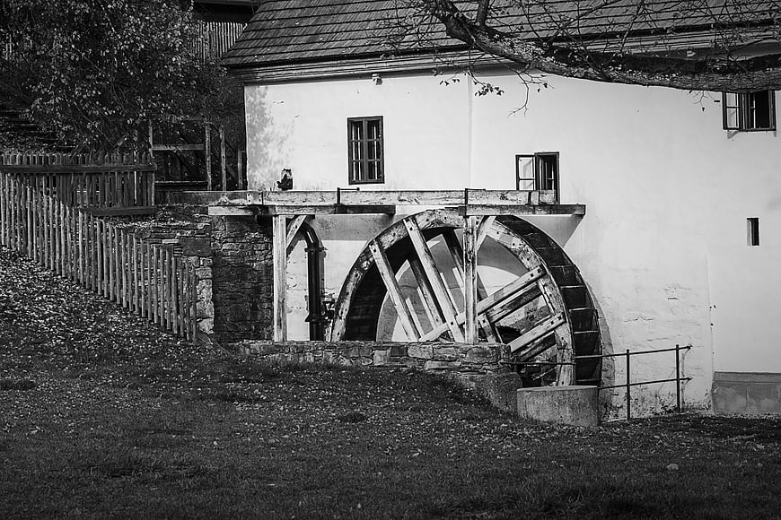 Black and white photo of an old wooden water mill wheel