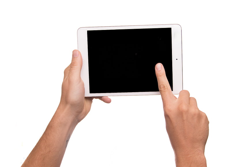 Hands holding white tablet with black screen on white background