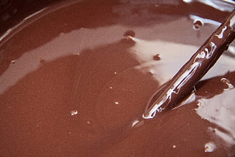 Close-up of melted chocolate being stirred with a wooden spoon