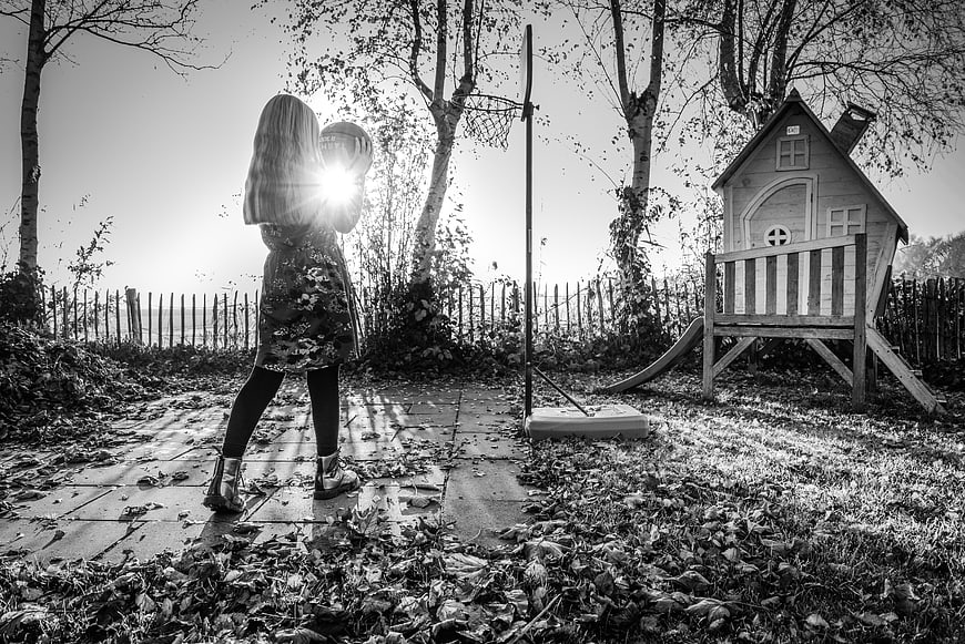 Girl holding basketball in backyard with playhouse