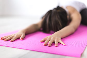 Woman stretching hands on pink yoga mat