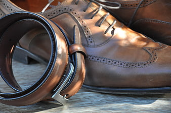 Brown Leather Belt And Brogue Dress Shoes On Wooden Surface