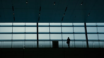 Silhouette of a person standing in a modern glass building interior