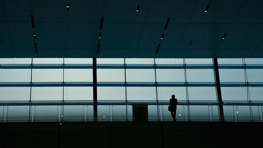 Silhouette of a person standing in a modern glass building interior