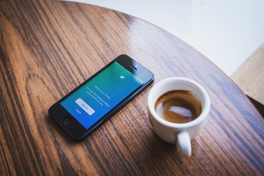 Smartphone with Twitter App and Espresso on Wooden Table