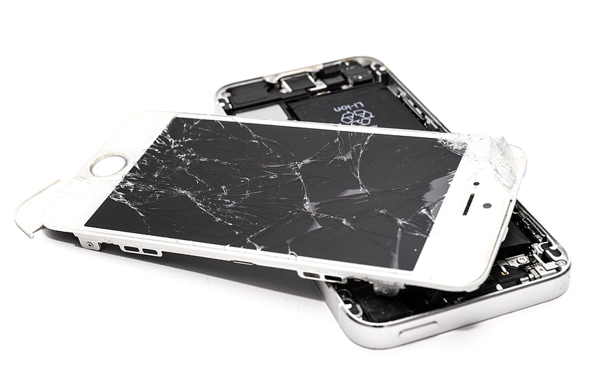 Broken white smartphone with shattered screen on white background