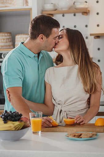 Romantic couple kissing in kitchen with fresh fruit breakfast