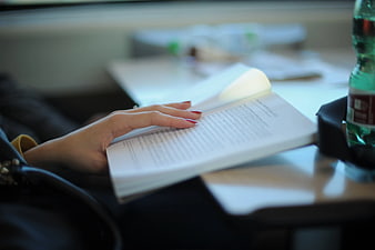 Woman Reading Book on Train with Red Nails
