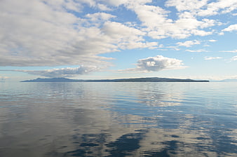 Serene ocean view with distant island and cloud reflections