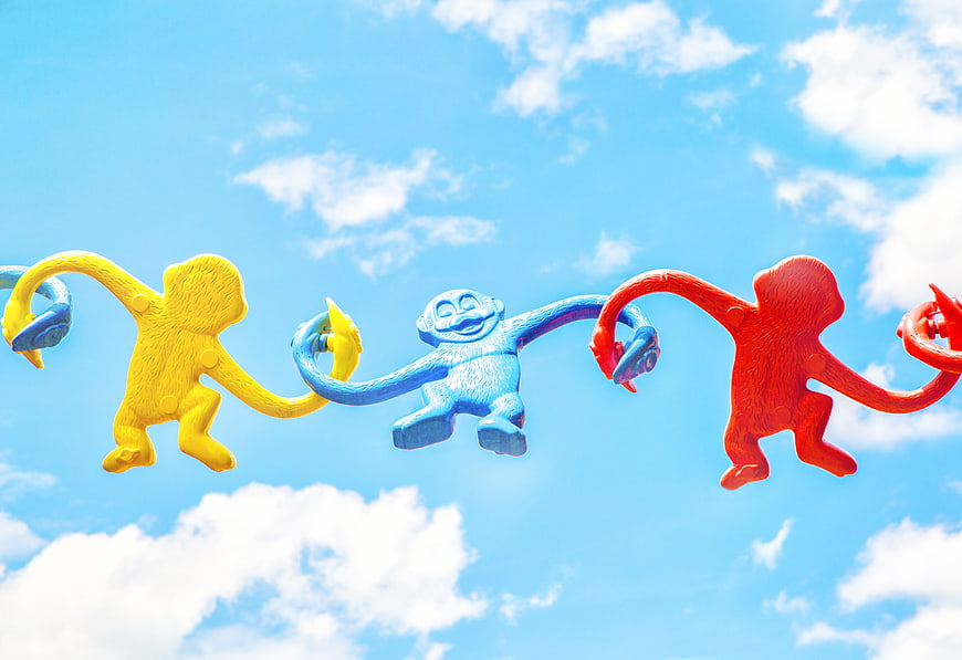 Colorful monkey sculptures hanging against blue sky