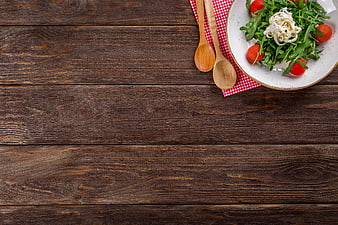 Fresh arugula salad with tomatoes and cheese on rustic wood