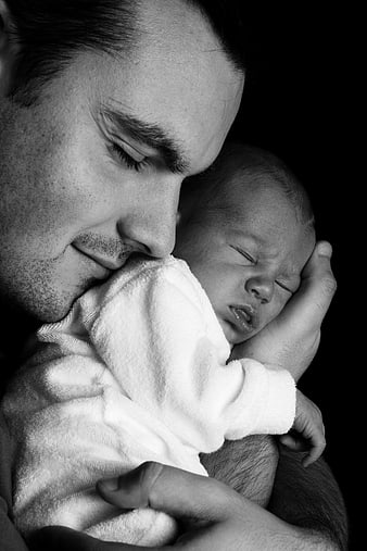 Black and white portrait of father holding sleeping newborn baby
