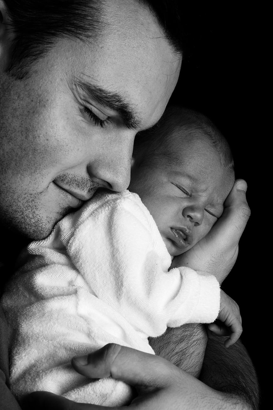 Black and white portrait of father holding sleeping newborn baby