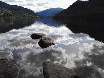 Serene Norwegian Lake with Mountain Reflections and Foreground Rocks