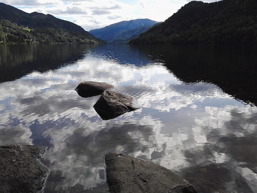 Serene Norwegian Lake with Mountain Reflections and Foreground Rocks