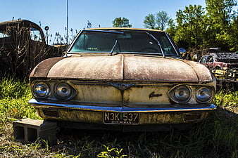 Front view of rusty vintage car in junkyard