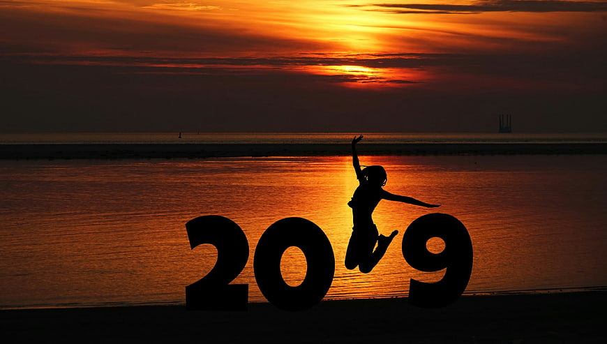 Silhouette of woman jumping between 2019 numbers at sunset