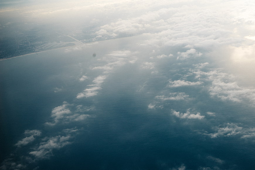 Aerial view of ocean coastline with scattered clouds and sunlight
