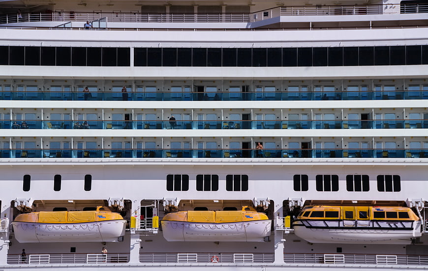 Cruise ship side with yellow lifeboats and balconies