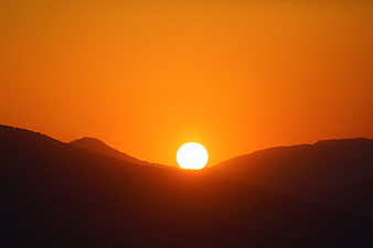 Vibrant Orange Sunset Over Silhouetted Mountain Ridges