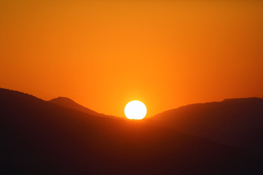 Vibrant Orange Sunset Over Silhouetted Mountain Ridges