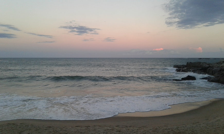 Serene Beach Sunset with Gentle Waves and Rocky Shoreline