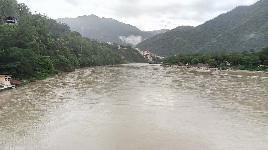 Wide muddy Ganges river flowing through lush green mountain valley