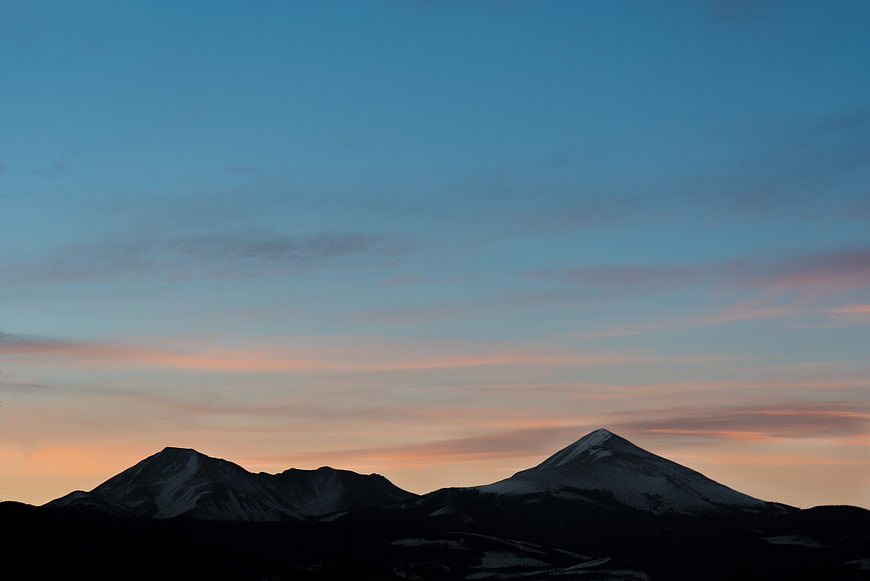Snow-Capped Mountain Peaks at Sunset with Blue Sky