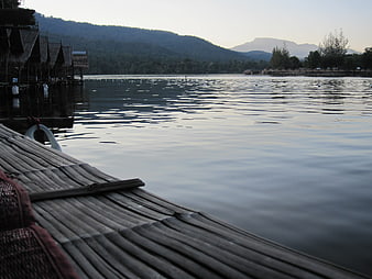 Bamboo raft on calm lake with stilt houses and mountains