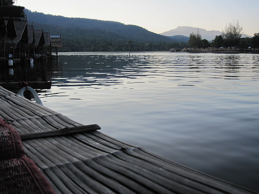 Bamboo raft on calm lake with stilt houses and mountains