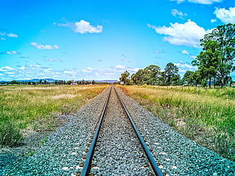 Railway Tracks Stretching Through Rural Landscape Under Blue Sky
