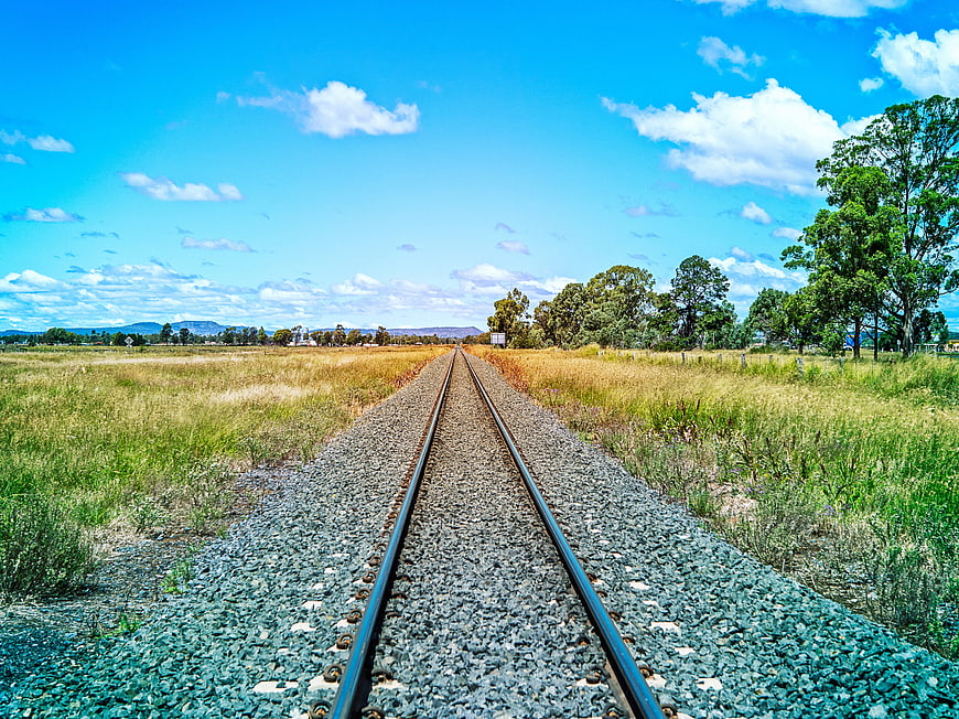 Railway Tracks Stretching Through Rural Landscape Under Blue Sky