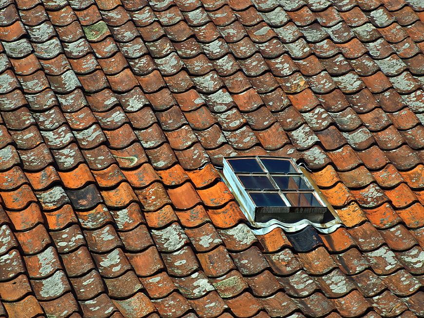 Weathered terracotta roof tiles with skylight window