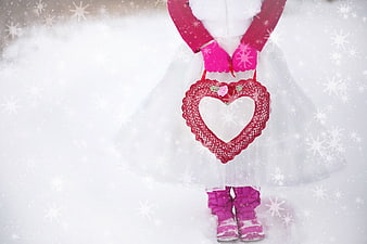 Child in white tutu holding red heart basket in snow