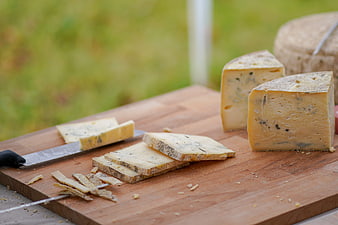 Sliced hard cheese on wooden cutting board with knife
